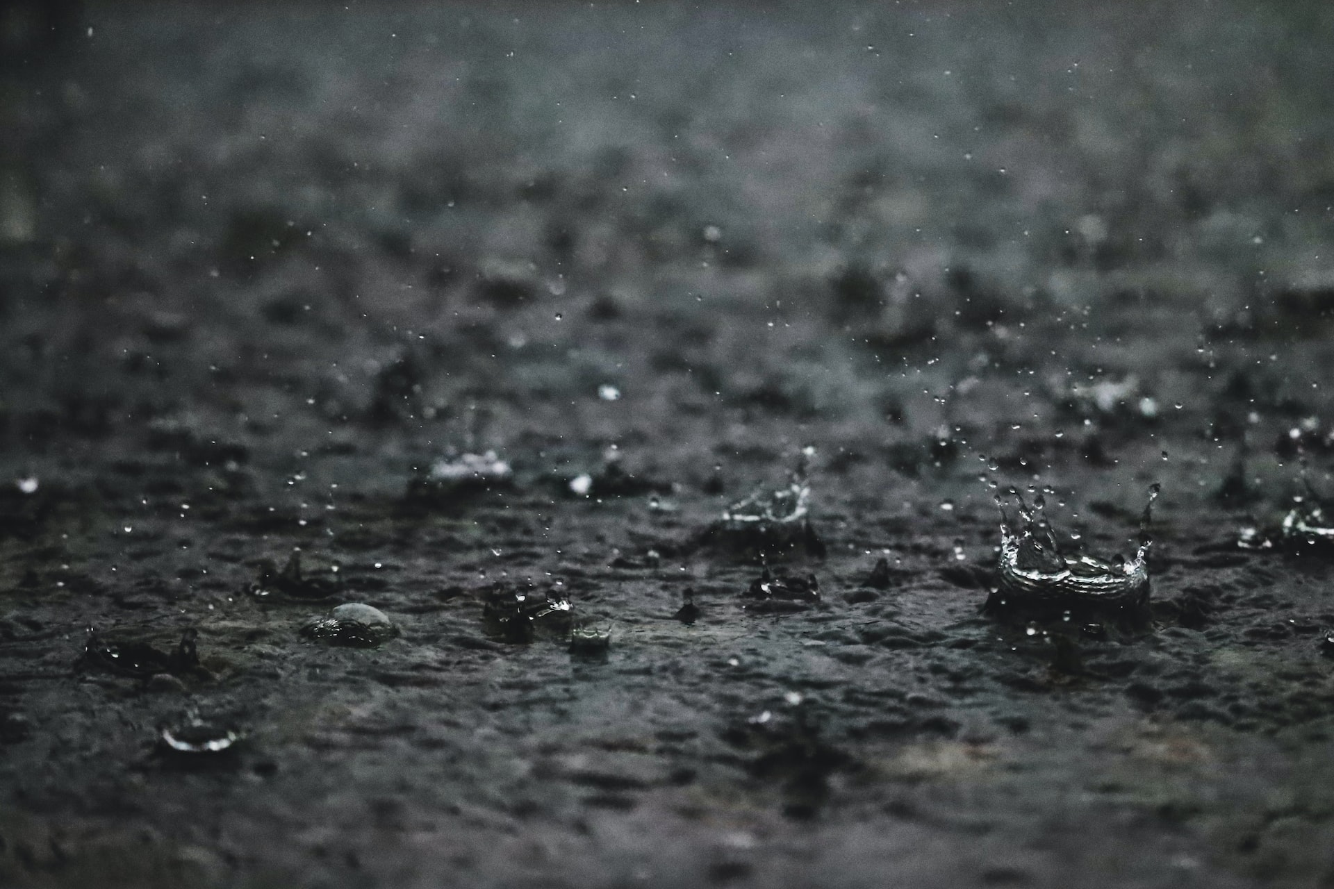 a black and white photo of rain falling on the ground